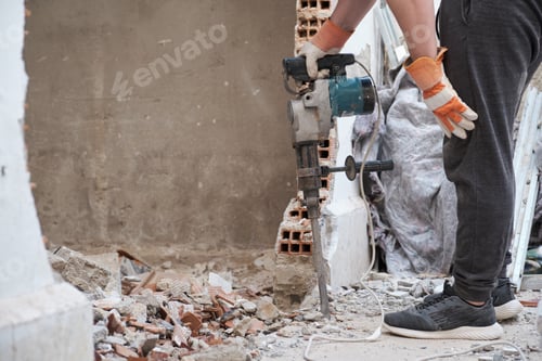 Preview: Unrecognizable man resting after using a jackhammer to drill into wall.