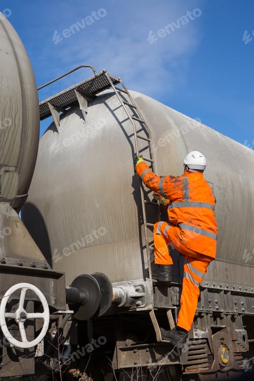 Preview: railway or manual worker climbing a ladder on the side of a freight tanker wagon to inspect high up