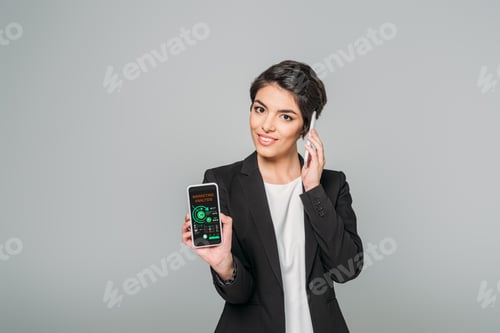 Preview: smiling mixed race businesswoman talking on smartphone and showing smartphone with marketing
