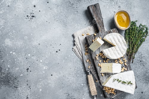 Preview: Delicious cheese brie and camembert on wooden board with herbs and nuts. Dairy French products.