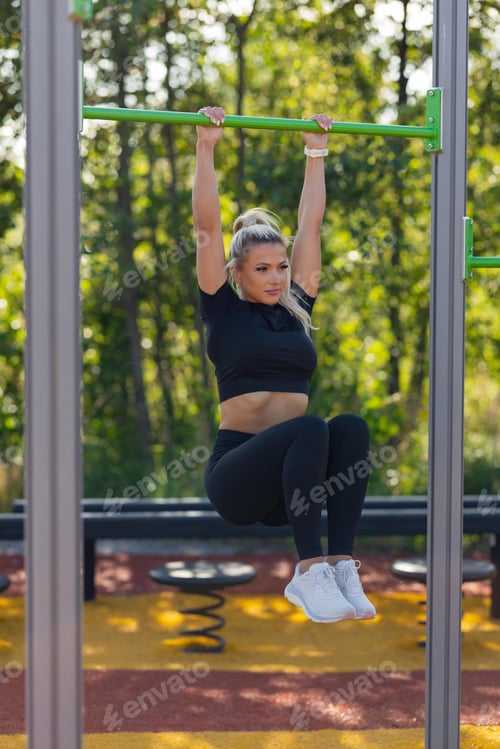 Preview: Woman practicing outdoor strength training on fitness equipment in park setting