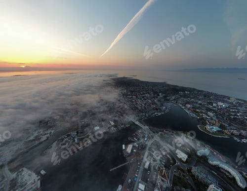 Preview: Aerial cityscape view with high buildings covered with fog against a scenic sunset