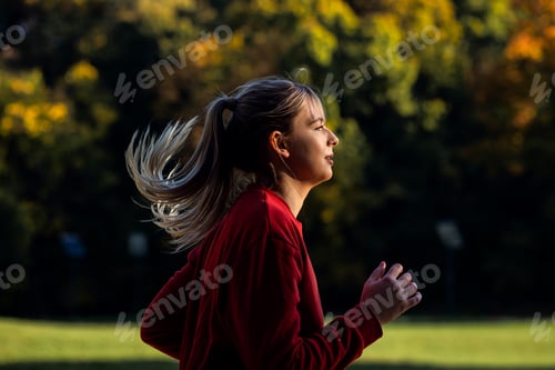 Preview: Side view of young woman running in park.