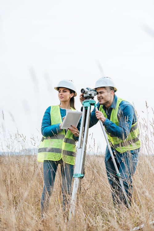 Preview: Surveyors working with digital level and using tablet in field