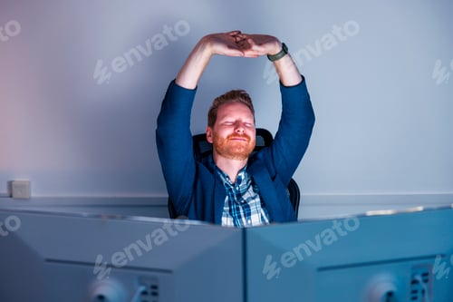 Preview: Businessman stretching at his desk while working late