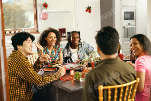 Preview: Happy friends enjoying in conversation and drinking wine during festive dinner at home party