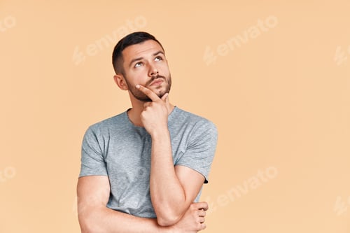 Preview: Young thoughtful man thinking and looking aside on copy space isolated on yellow background