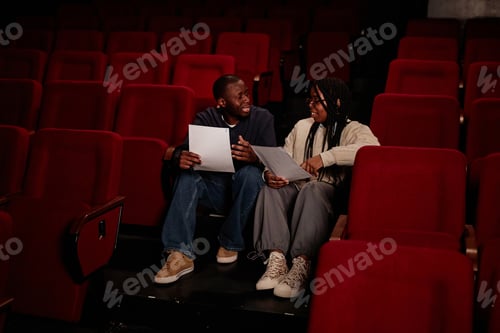 Preview: Two Performers Sitting on Floor in Theater