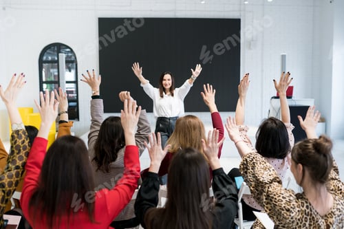Preview: A group of people sitting with their hands up in seminar.