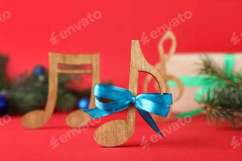 Preview: Wooden music note with blue bow on red background, closeup. Christmas celebration