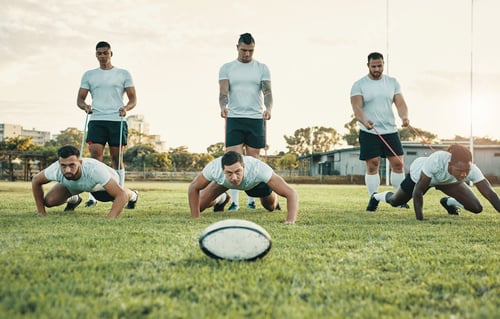 Preview: Cropped shot of a group of young rugby players training with bands on the field during the day