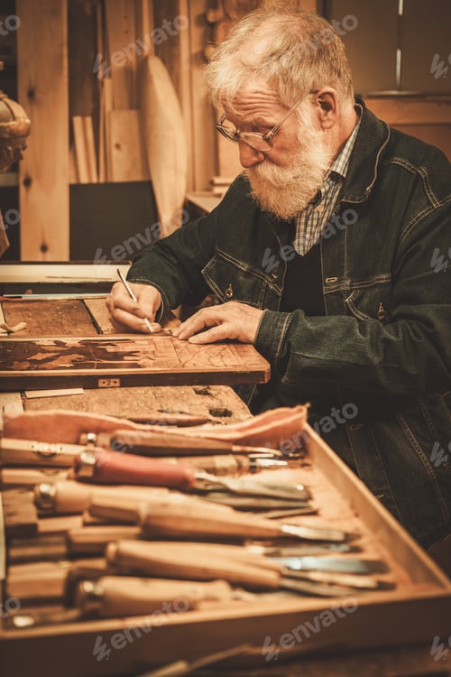 Preview: Senior restorer working with antique decor element in his workshop