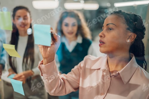 Preview: Focused businesswoman writing on sticky notes during brainstorming session