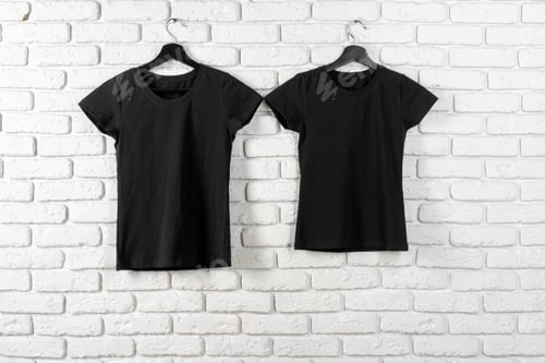 Preview: Black t-shirt hanging on a hanger against brick wall