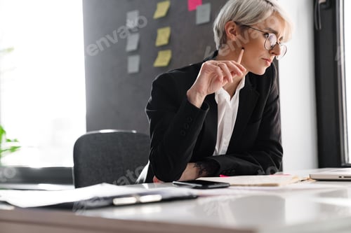 Preview: White-haired puzzled woman working with laptop while sitting at table