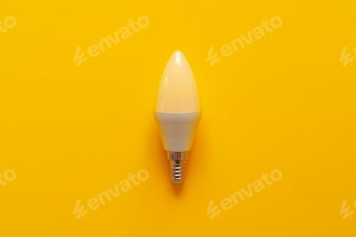 Preview: Light bulb on yellow paper background top view