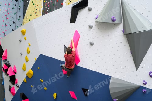 Preview: Man climber on artificial climbing wall in bouldering gym