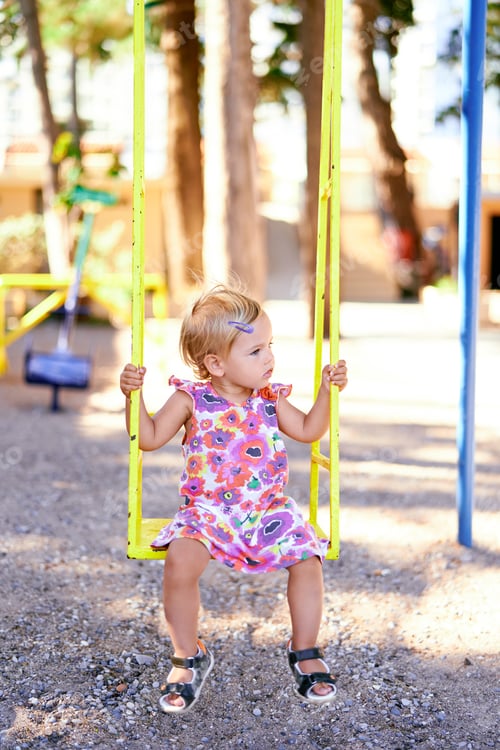 Preview: Little girl sitting on a swing in the playground