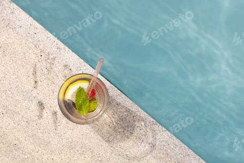 Preview: A refreshing drink with lemon and mint sits by a poolside with copy space