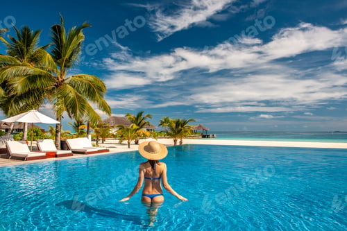 Preview: Woman with hat at beach pool in Maldives