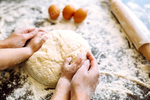 Preview: Close up hands of mother and son kneading a dough on a wooden table. Family cooking at home together