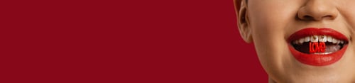 Preview: Close-up of unrecognizable woman holding plastic letters in mouth against red background