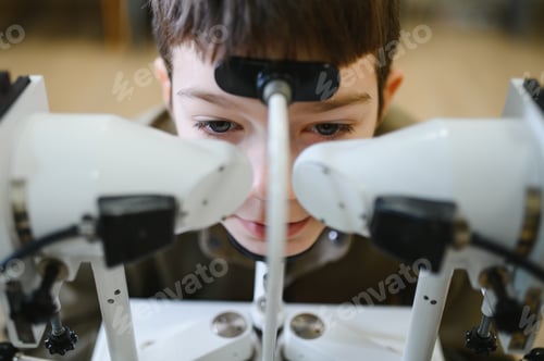 Preview: Boy undergoing eyesight examination with phoropter in ophthalmology clinic