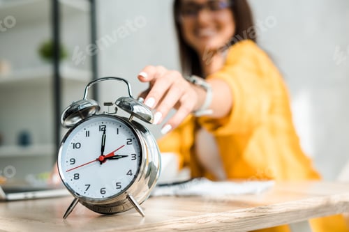 Preview: selective focus of female freelancer touching alarm clock