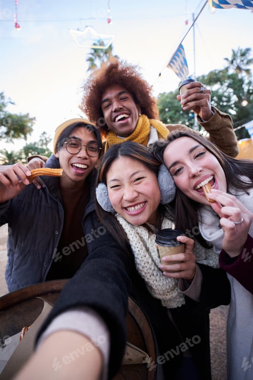 Preview: Vertical selfie phone looking camera of cheerful friends eating chocolate churros street food stall.