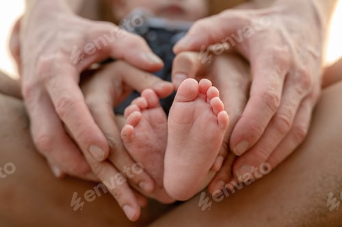 Preview: Close-up of baby's feet. Mother holding baby.Happy family at sunset.Holiday Family