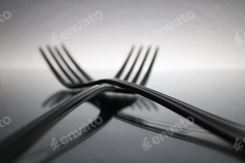 Preview: Intertwined forks on a reflective surface