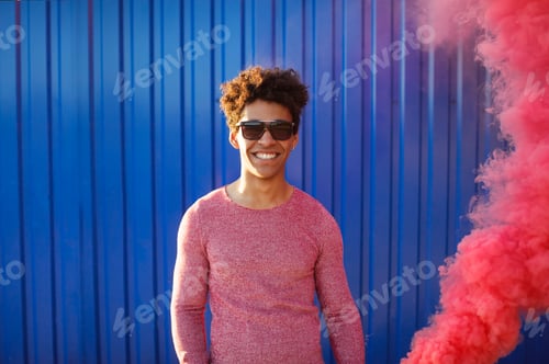 Preview: Young black man in a sweater standing next to blue wall