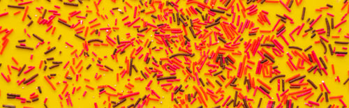 Preview: Top view of red and black sprinkles on yellow background, banner