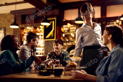 Preview: Happy waitress serving burgers and French fries to her customer in a bar.