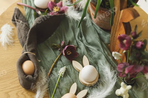 Preview: Stylish wooden bunny, spring flowers, natural eggs and napkin bunny ears on rustic table