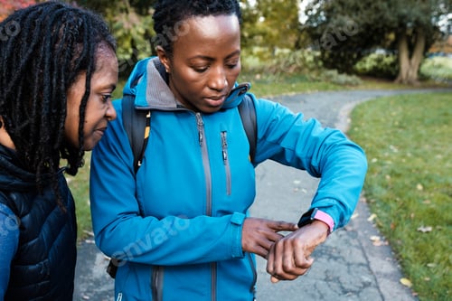 Vista previa: Two mature black women checking smart watch in a park.