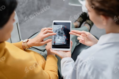 Preview: Closeup of dentist holding tablet with X ray images