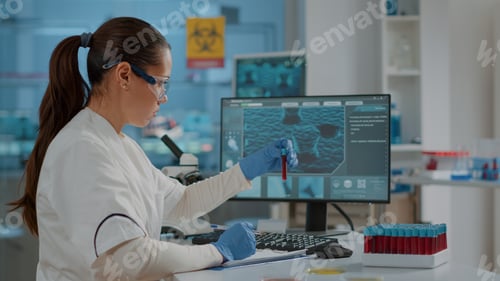 Preview: Biologist analyzing liquid in test tube and using computer