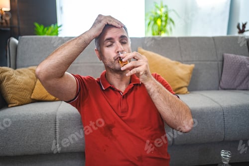 Preview: Mature man sitting on the floor and drinking alcohol