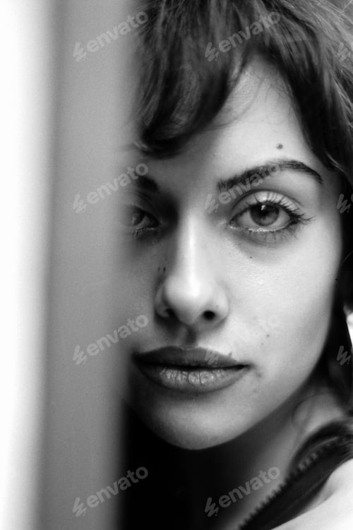 Preview: Monochrome head-shot of young woman looking at camera.