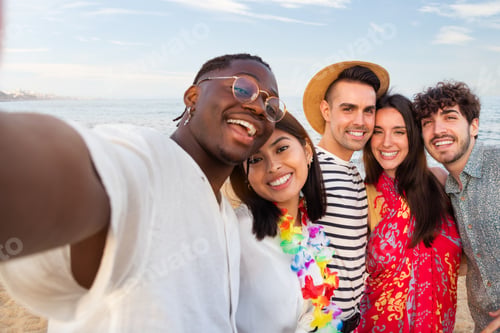 Preview: Group of happy, multiracial friends looking at camera take selfie together outdoors in the beach.