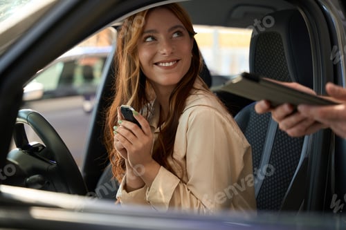 Preview: Joyous woman seated in vehicle smiling at car sales consultant