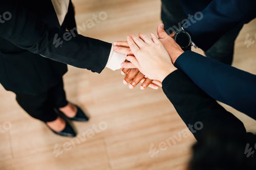 Preview: Above view captures business professionals stacking hands in circle, highlighting the strength of
