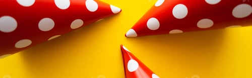 Preview: Top view of red dotted party caps on yellow background, banner