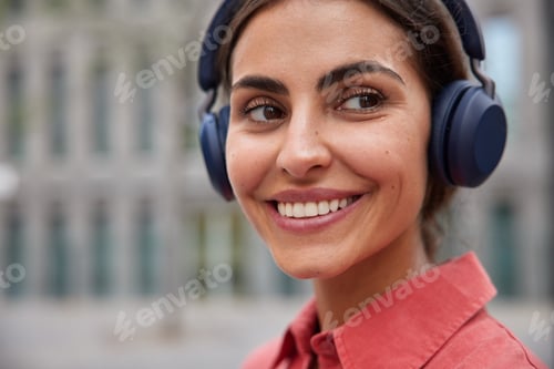 Preview: Close up shot of happy brunette woman with minimal makeup smiles toothily looks somewhere listens so