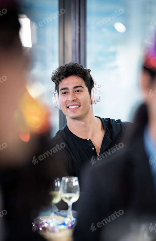 Preview: Handsome young DJ with headphones and digital mixer paying song with hands raised