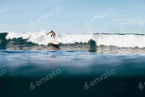 Preview: young man riding ocean wave on surfboard