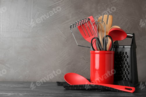 Preview: Holder with kitchen utensils on grey table against grey stone background. Space for text