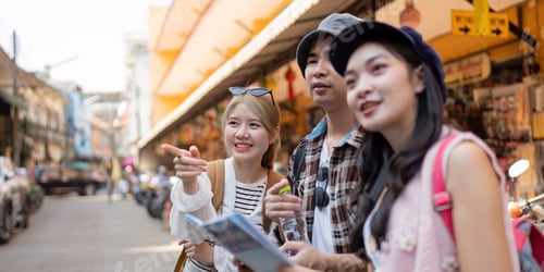 Preview: Friends exploring a vibrant market, studying a map while traveling and sharing moments of discovery