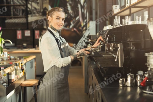 Preview: Tattooed barista making coffee in professional coffee machine